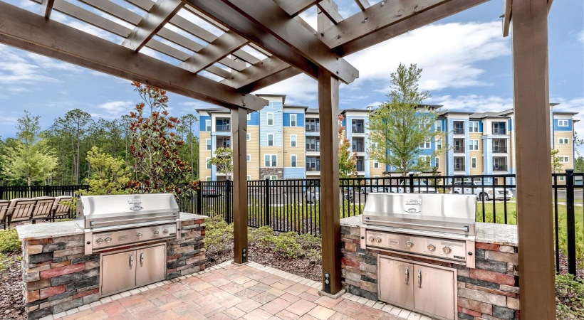 a patio with a wood railing and a brick patio with a building in the background